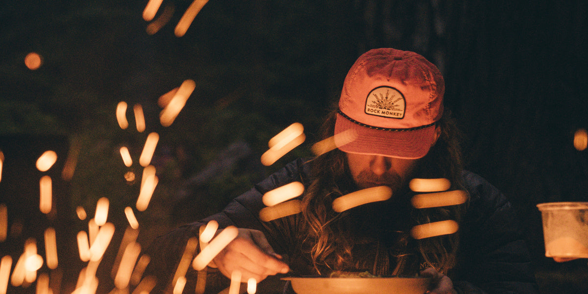 Campfire sparks around a man in an orange RCKMNKY hat - 2 hats for $55